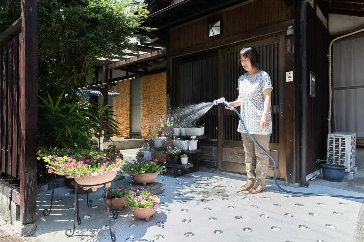 玄関で水やりをする女性